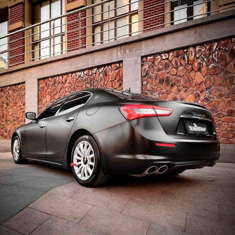 Luxury sedan fully wrapped in TeckWrap Black Matte Vinyl (CM01M), parked outdoors, emphasizing the wrap's sophisticated matte appearance and flawless automotive styling.