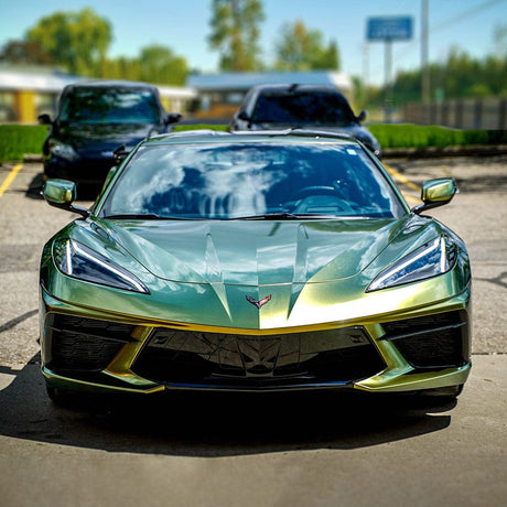 Front view of a sleek sports car wrapped in TeckWrap Honey Lime (RD12-HD) vinyl, emphasizing the wrap’s glossy, vibrant gold and lime-green color transition under sunlight, providing an eye-catching, premium appearance.